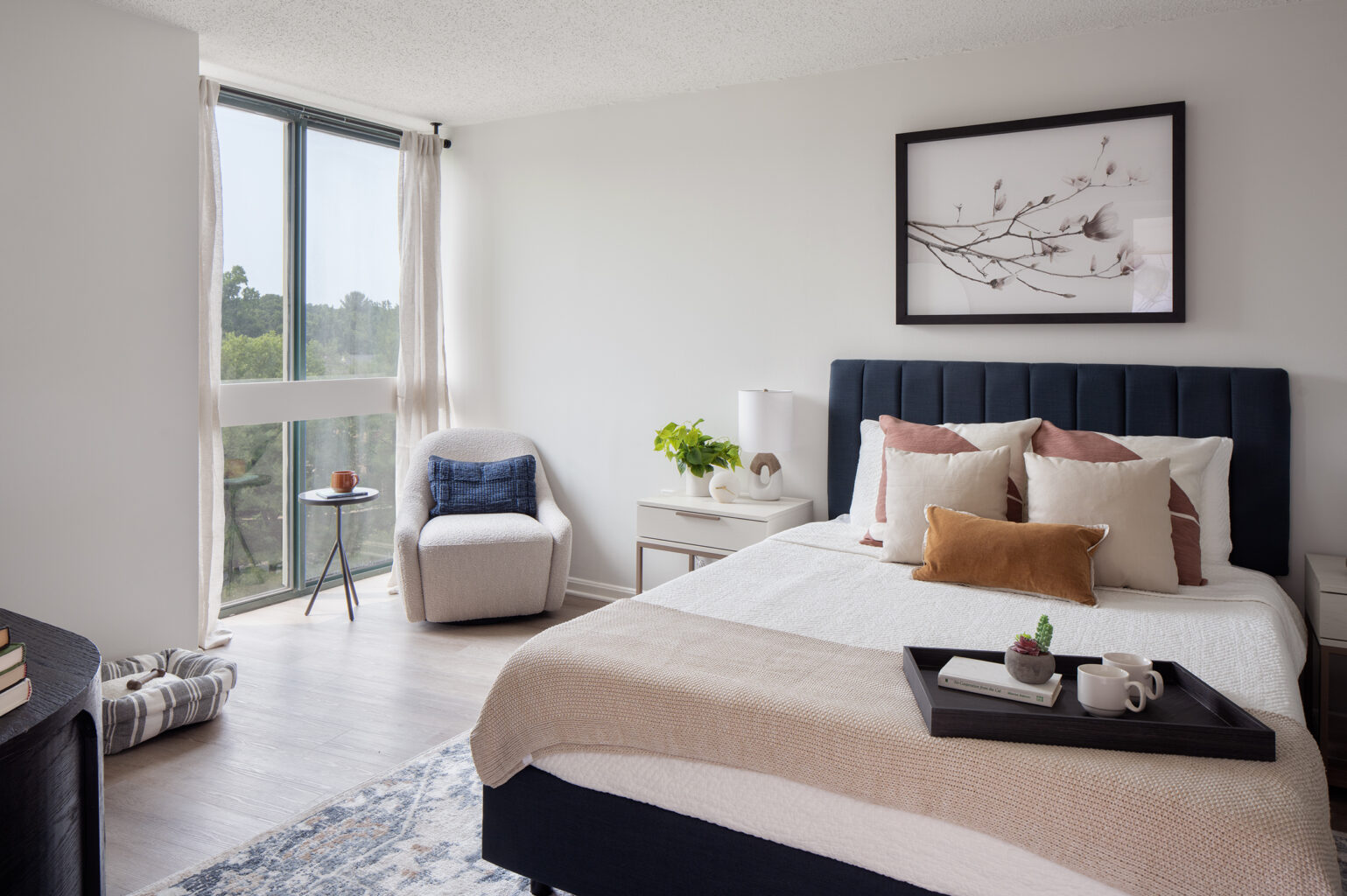 A modern, organically decorated bedroom with floor to ceiling windows and tree views.