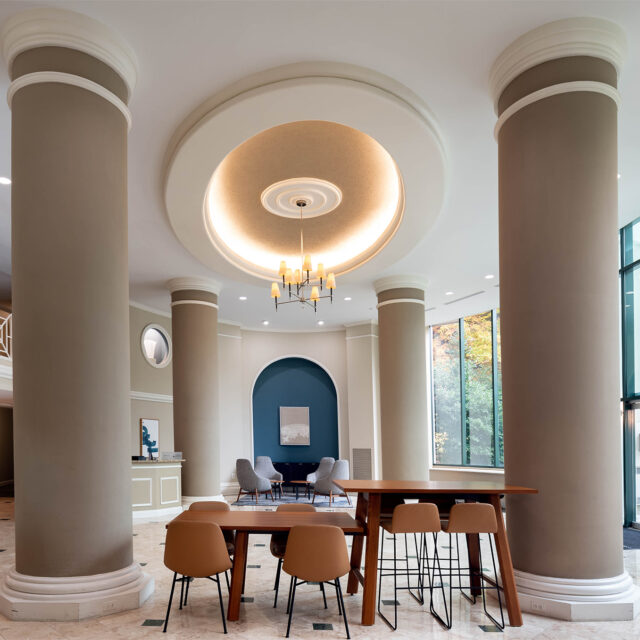 A grand two-story lobby with floor-to-ceiling windows and large columns and seating nooks.